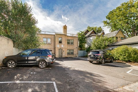 A parking lot with two cars and a building in the background.