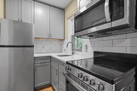 A kitchen with a stove, refrigerator, and microwave.