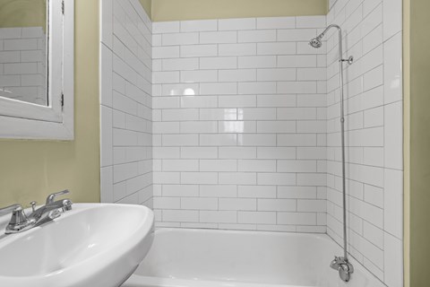 A white sink is in front of a white tiled shower.