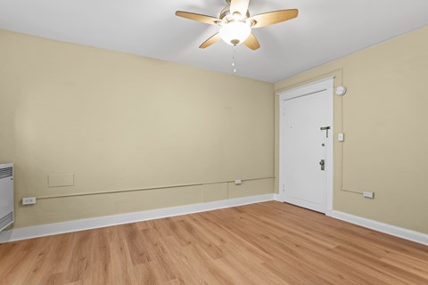 A room with a ceiling fan and a white door.