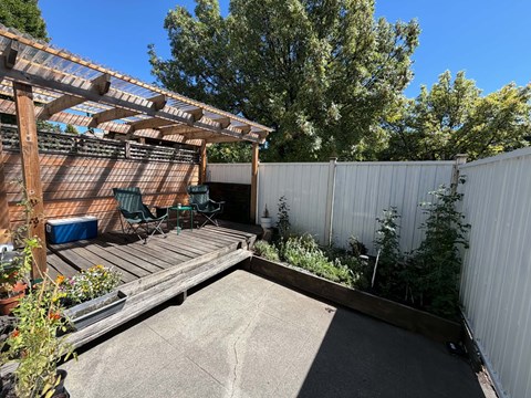 A backyard with a wooden deck and a white fence.