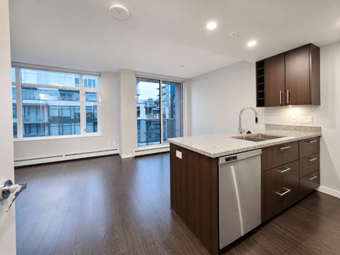 A kitchen with a sink, dishwasher and wooden floors.