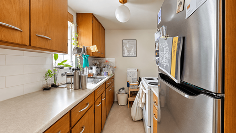 A kitchen with a refrigerator, sink, and cabinets.