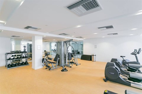 A gym with a variety of equipment including weights, a bench press, and a treadmill.