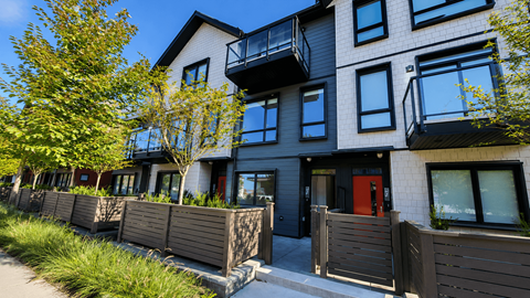 A modern apartment building with balconies and a red door.