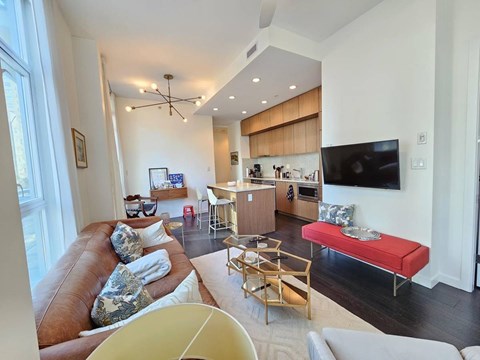 A living room with a brown leather couch and a red bench.