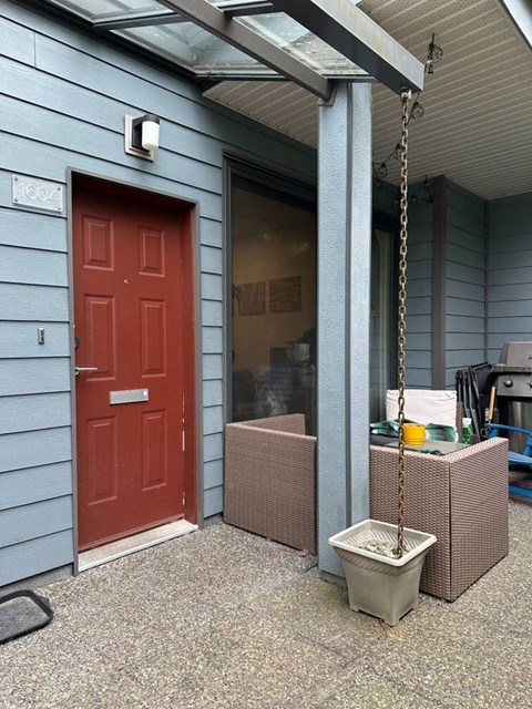 A red door is on the left side of a blue building.