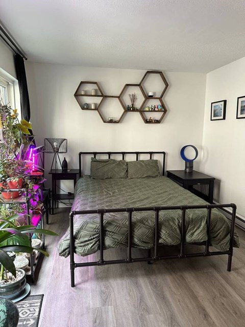A bedroom with a bed, nightstand, and a wall decoration.