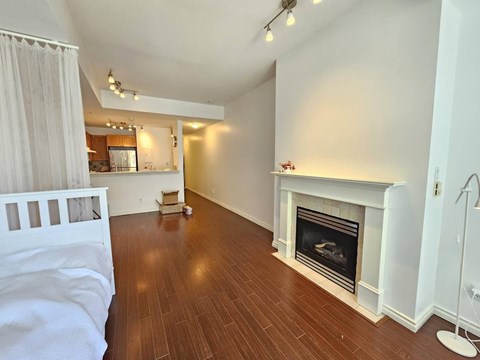 A white bedroom with a fireplace and wooden floors.