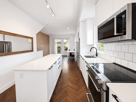 A modern kitchen with white cabinets and black appliances.
