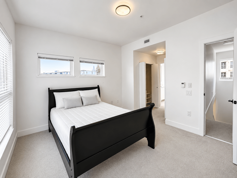A bedroom with a large bed and a carpeted floor.