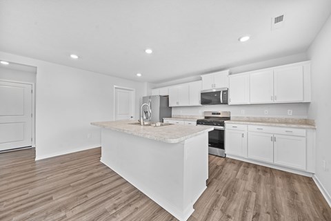 A kitchen with white cabinets and a wooden island.