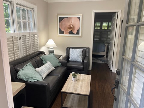 A living room with a black couch and a painting on the wall.