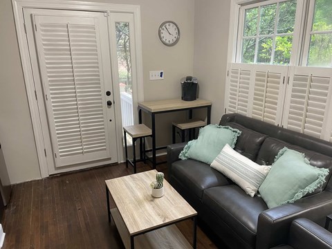 A living room with a black couch and a wooden table.