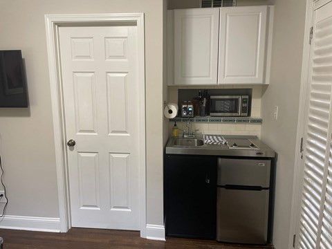 A white door is on the left and a black fridge is on the right.