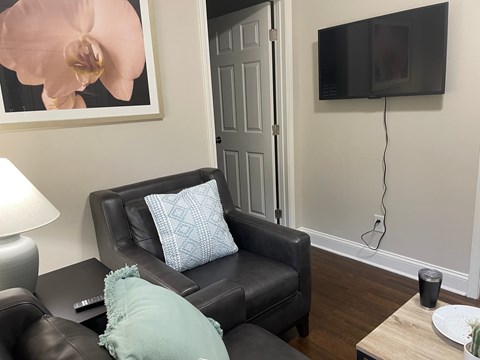 A black leather couch with a blue pillow and a remote control on it.