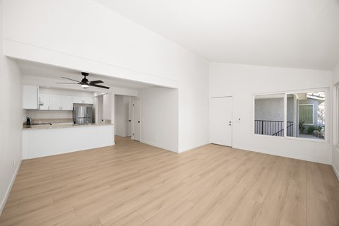A spacious room with wooden flooring and a ceiling fan.