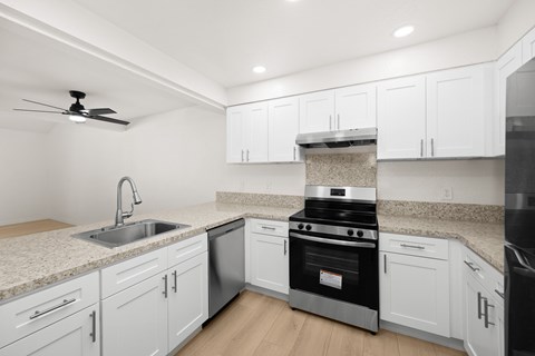 A modern kitchen with white cabinets and a black stove top oven.