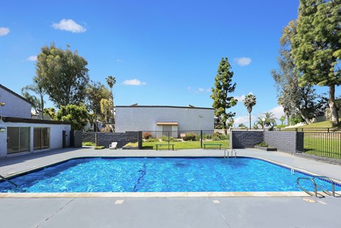 A swimming pool surrounded by a fence and trees.