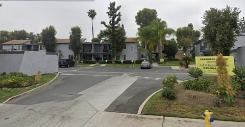 A street view of a residential area with houses and a yellow sign that reads "Cambridge".