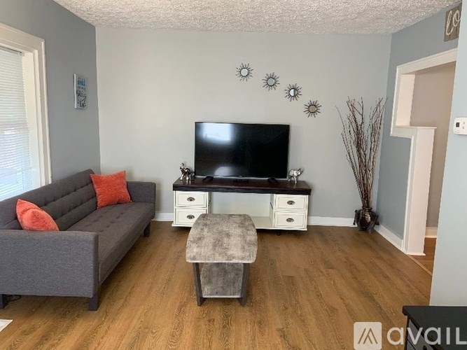 A living room with a grey couch, a black TV, and a grey ottoman.