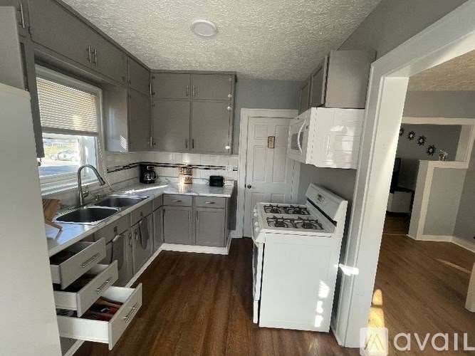 A kitchen with white appliances and wooden floors.