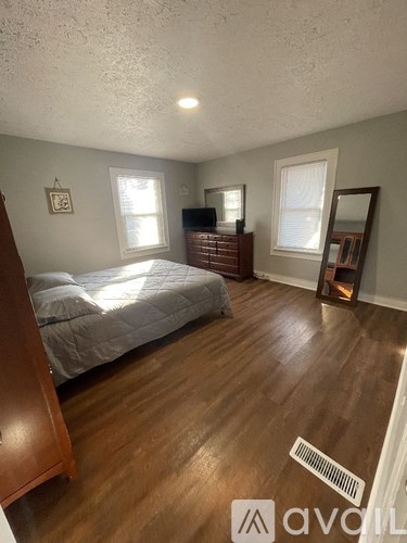 A bedroom with a bed, dresser, mirror, and window.
