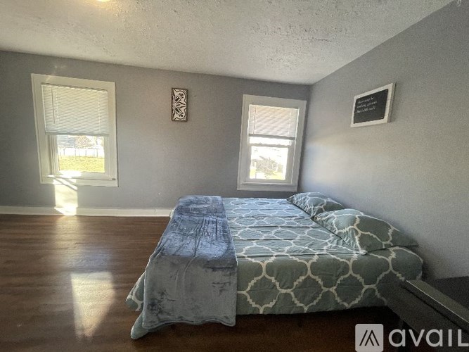A bedroom with a bed and two windows.