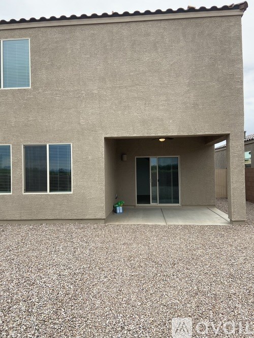 A house with a brown stucco exterior and a gravel driveway.