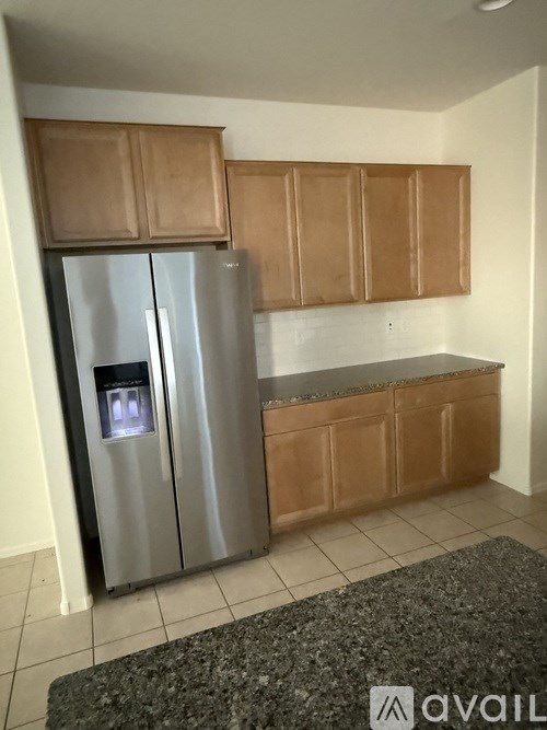 A kitchen with a stainless steel refrigerator and wooden cabinets.
