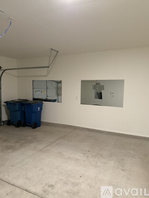 A room with a white wall and a blue trash bin.