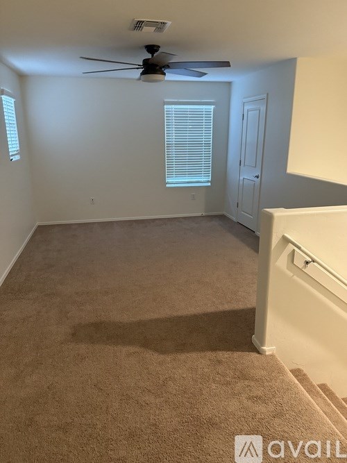 A room with a carpeted floor and a ceiling fan.