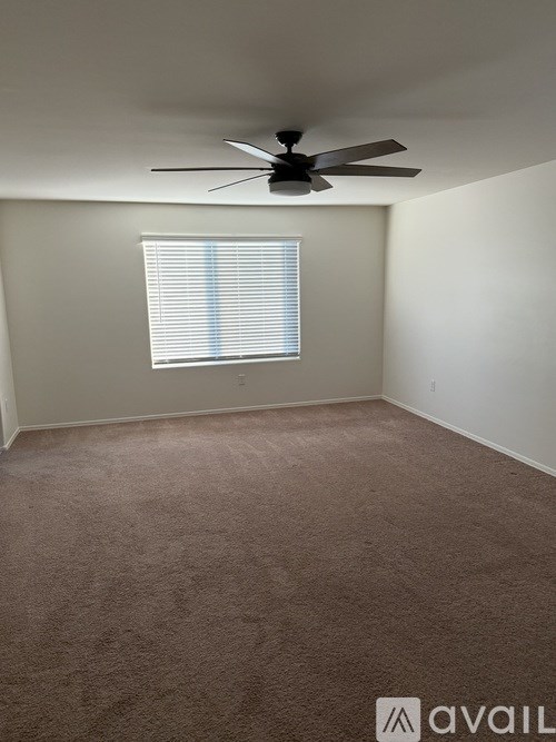 A room with a ceiling fan and a window with blinds.