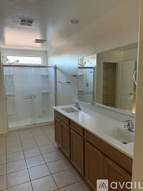 A bathroom with a sink, mirror, and shower.