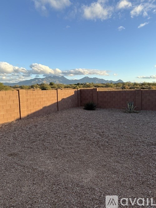 A backyard with a gravel ground and a fence.