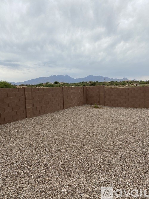 A backyard with a brown fence and gravel ground.