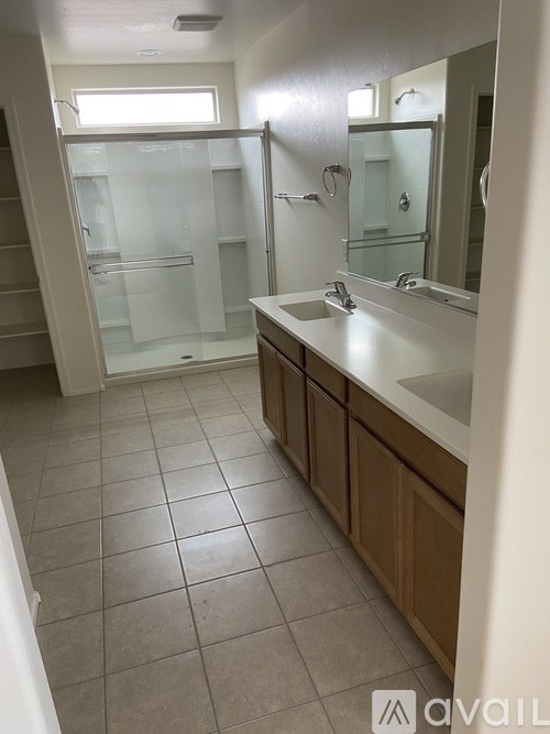 A bathroom with a sink, mirror, and shower.