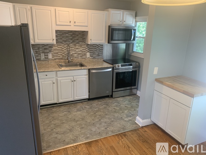A kitchen with white cabinets and a black refrigerator.