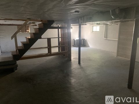 A spacious basement with a staircase and a pole.