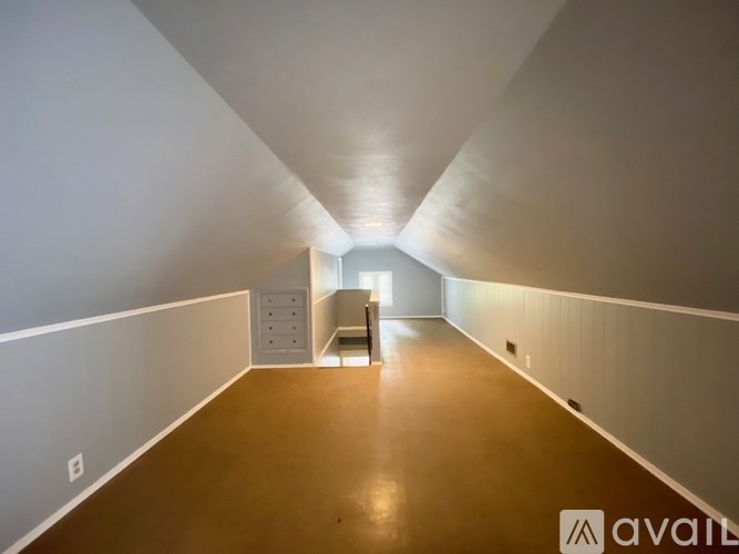 A long, empty hallway with a cabinet and a door at the end.