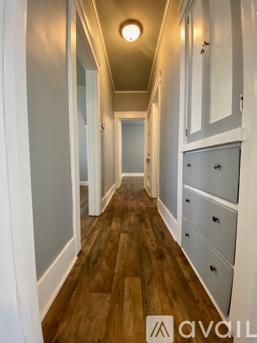 A long hallway with wood floors and white walls.