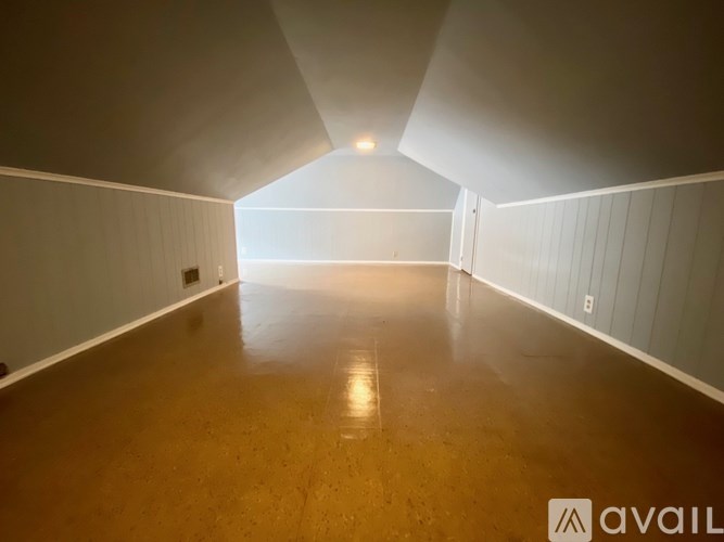 A long, empty hallway with wooden floors and white walls.