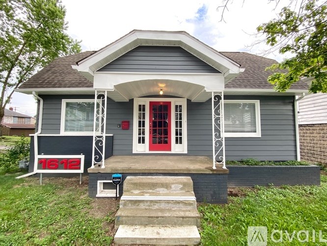 A house with a red door and a porch with a white railing.