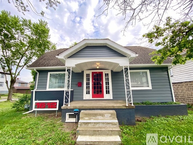 A house with a red door and a porch with a white railing.