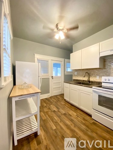 A kitchen with white cabinets and a wooden floor.