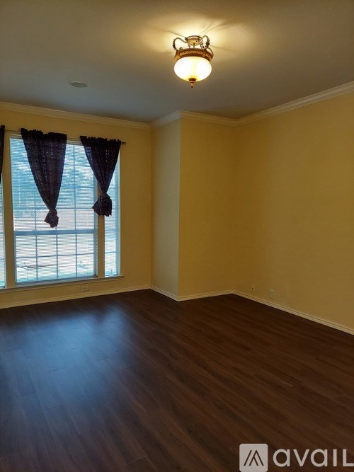 A room with wooden floors and a window with curtains.