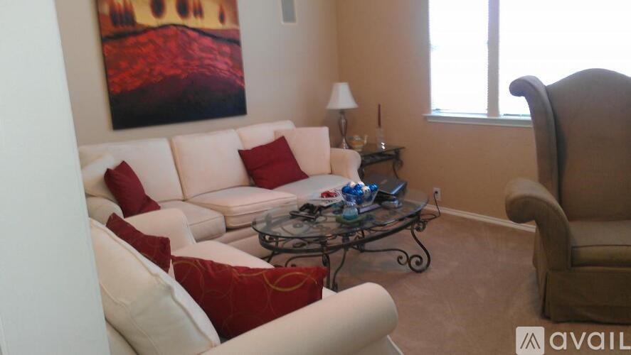 A living room with a white couch, a brown chair, and a painting on the wall.