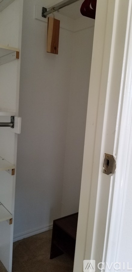 A white door with a handle and a small square hole in the wall.