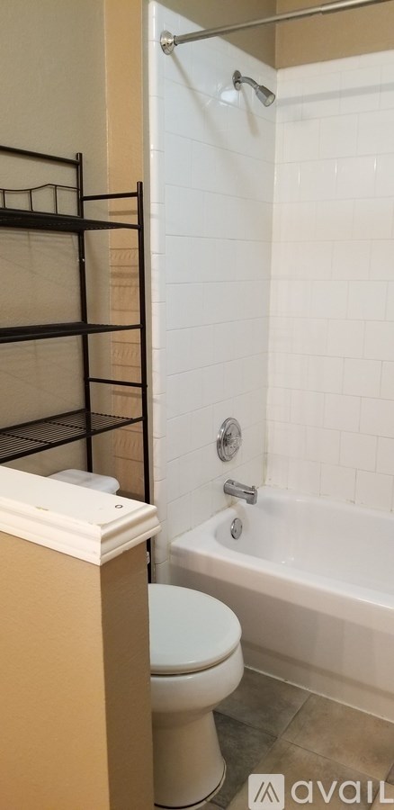 A white toilet sits next to a white bathtub in a bathroom.