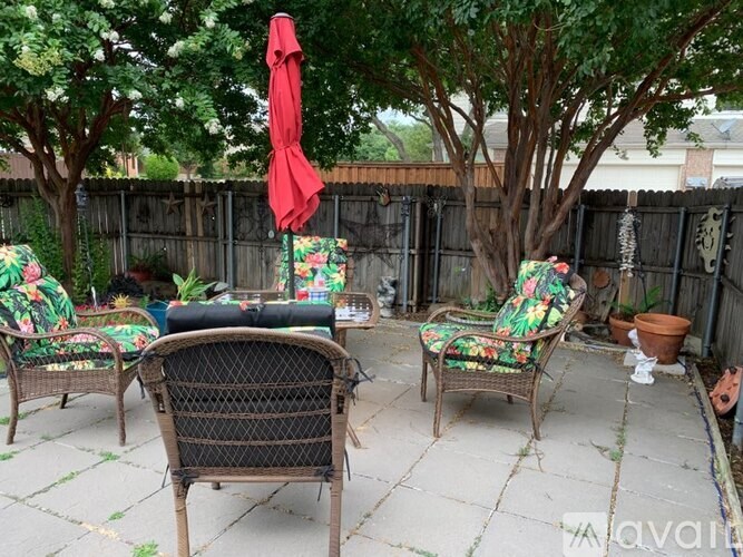 A patio with a table, chairs, and an umbrella.